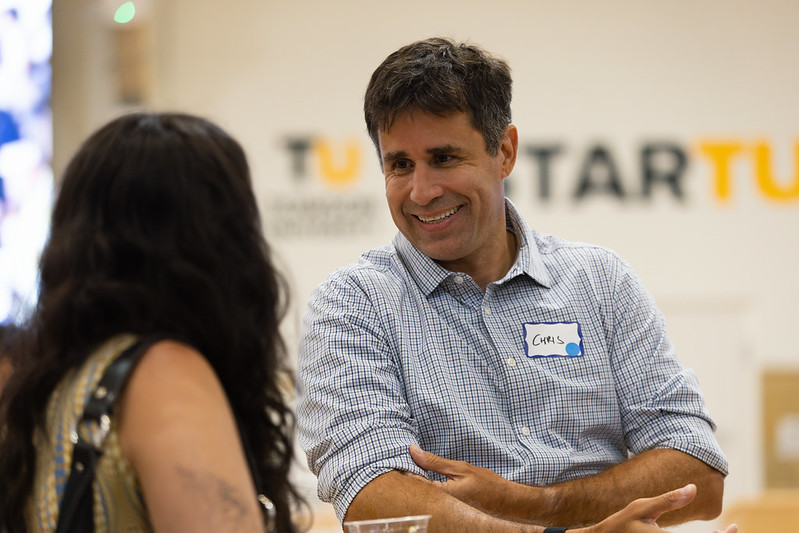 Chris Brandt, UpSurge Baltimore’s new CEO, wearing his event name tag and smiling in conversation with an attendee at an event.